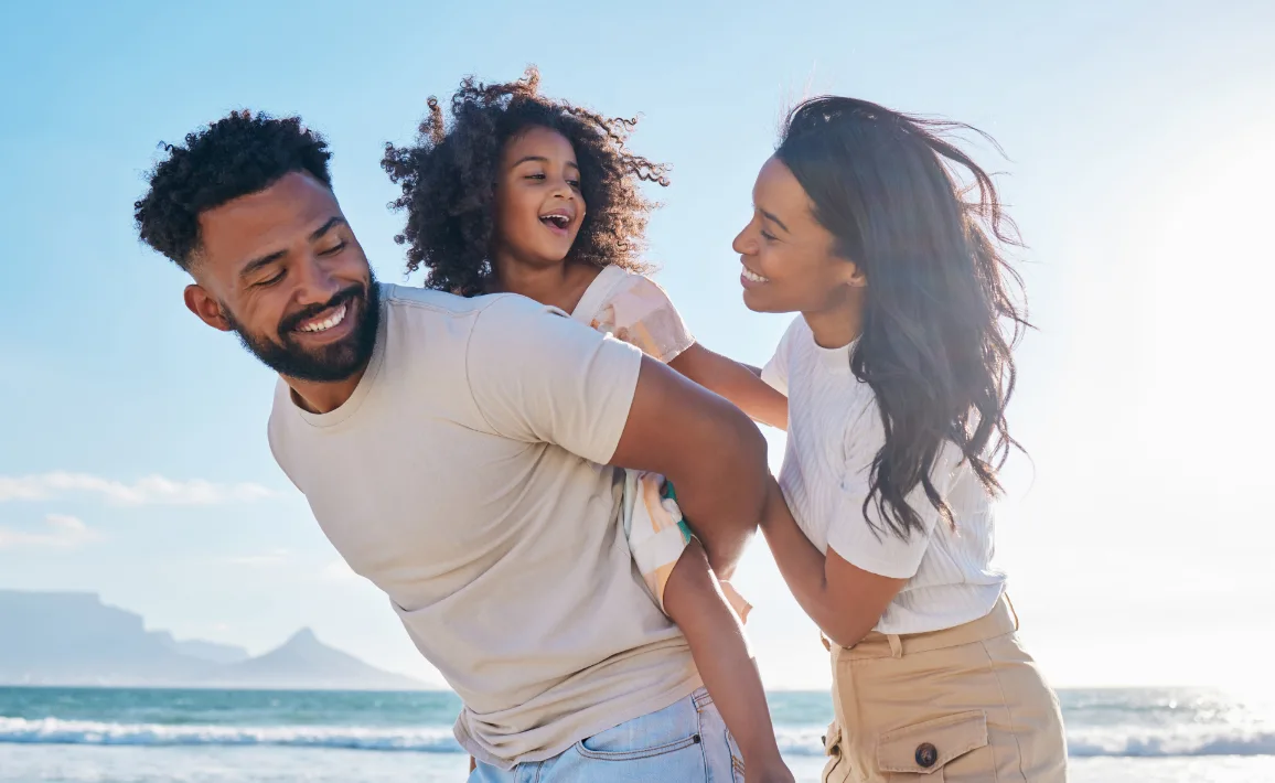 man, woman  and child on beach on sunny day smiling