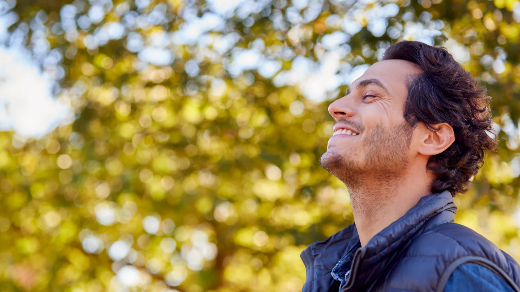 man smiling in front of foliage