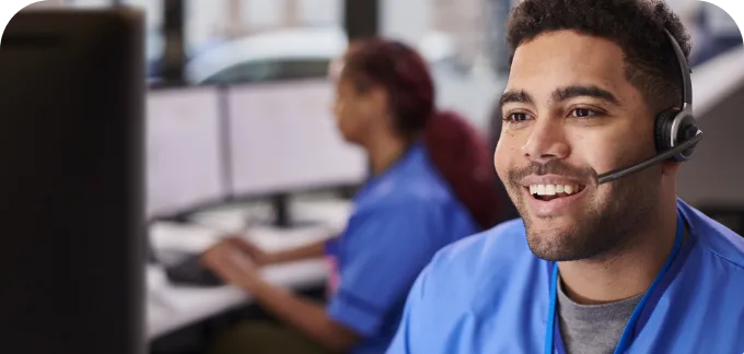 Nurse with headset in call center setting smiling at computer monitor