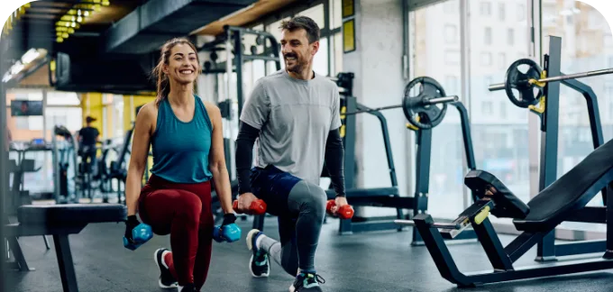Couple smiling at each other while working out in a gym setting