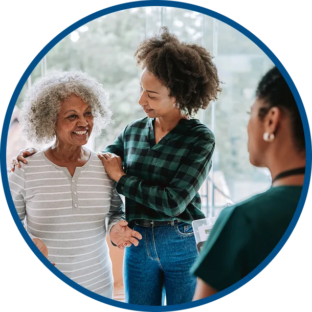 Care coordinator talking with an older woman and her daughter during a healthcare visit.