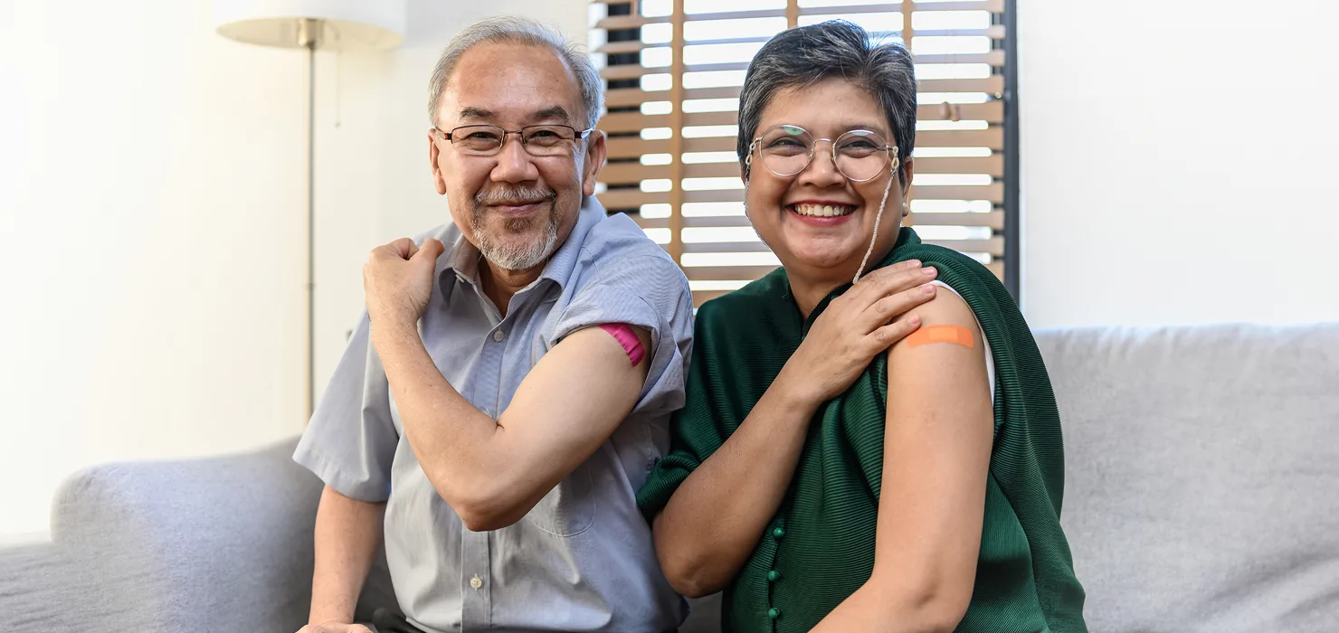 A man and woman showing off their band-aids from their vaccination