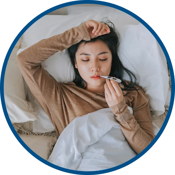 woman lying in bed taking her temperature with a thermometer