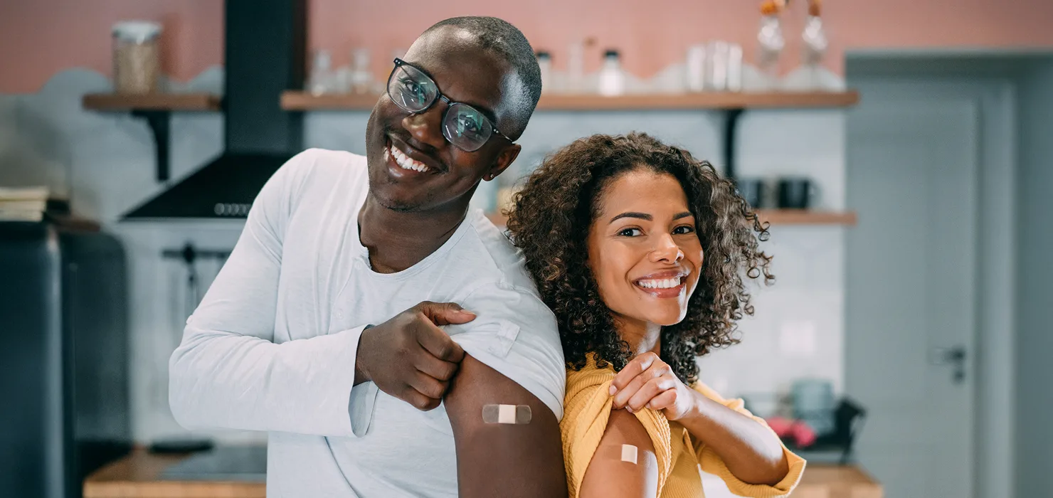 young black African American couple smiling, showing their bandages after getting vaccinated