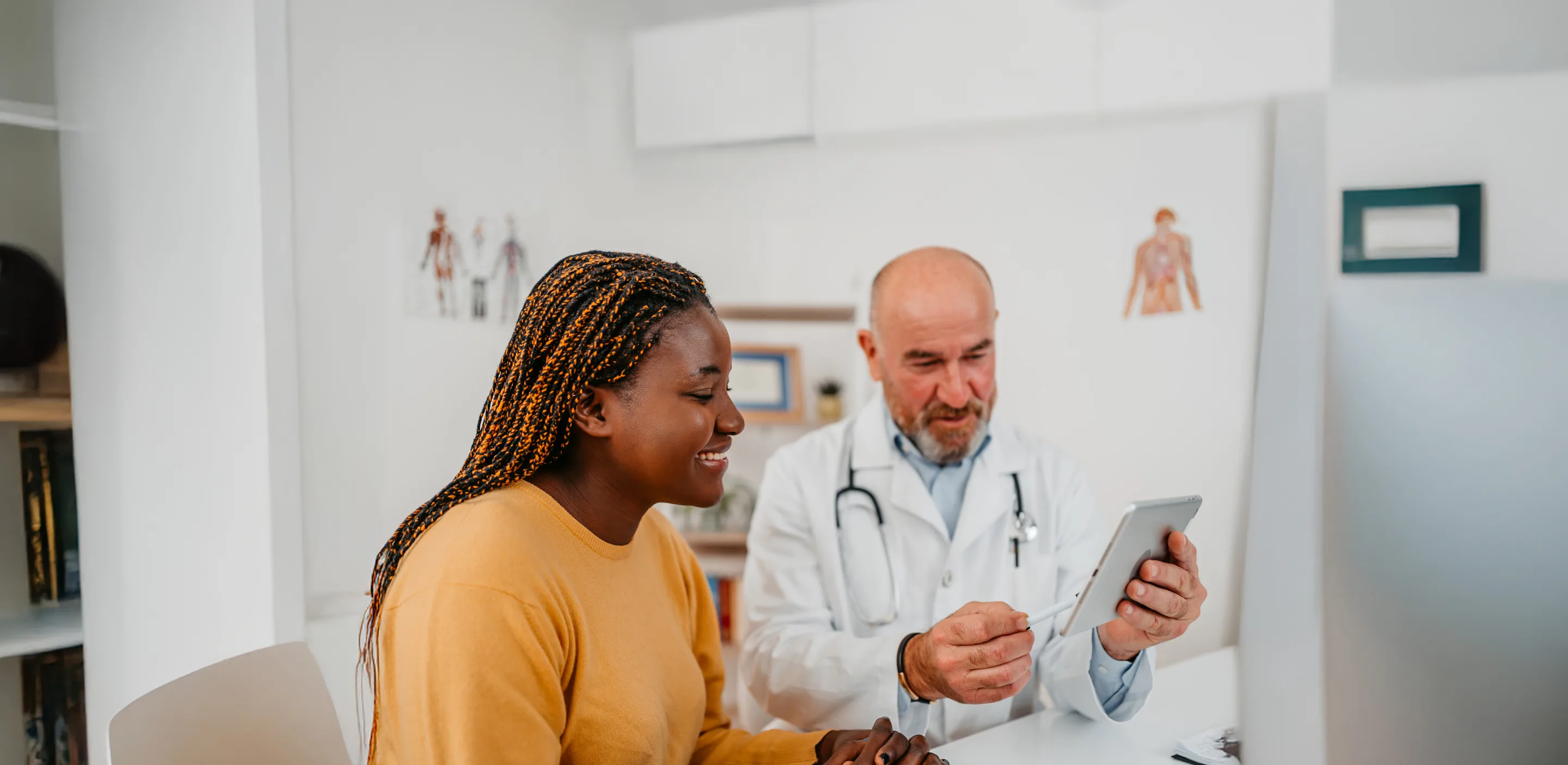 Dr and Patient smiling in examine room while reviewing on tablet