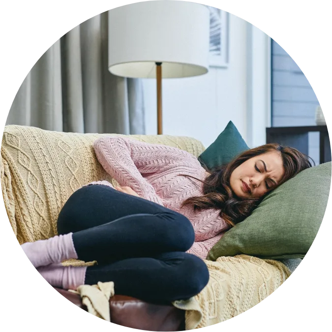 Girl on couch clutching stomach