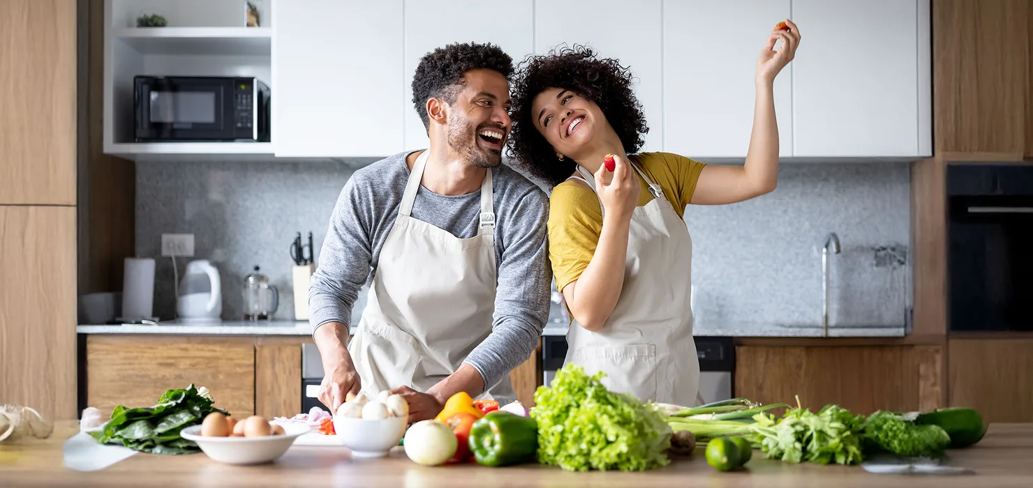 young black African American couple smilingwhile they cook in the kitchen