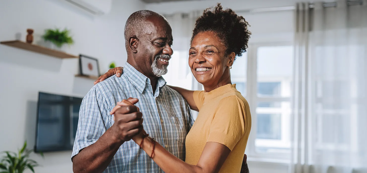 older black couple smiling & dancing at home