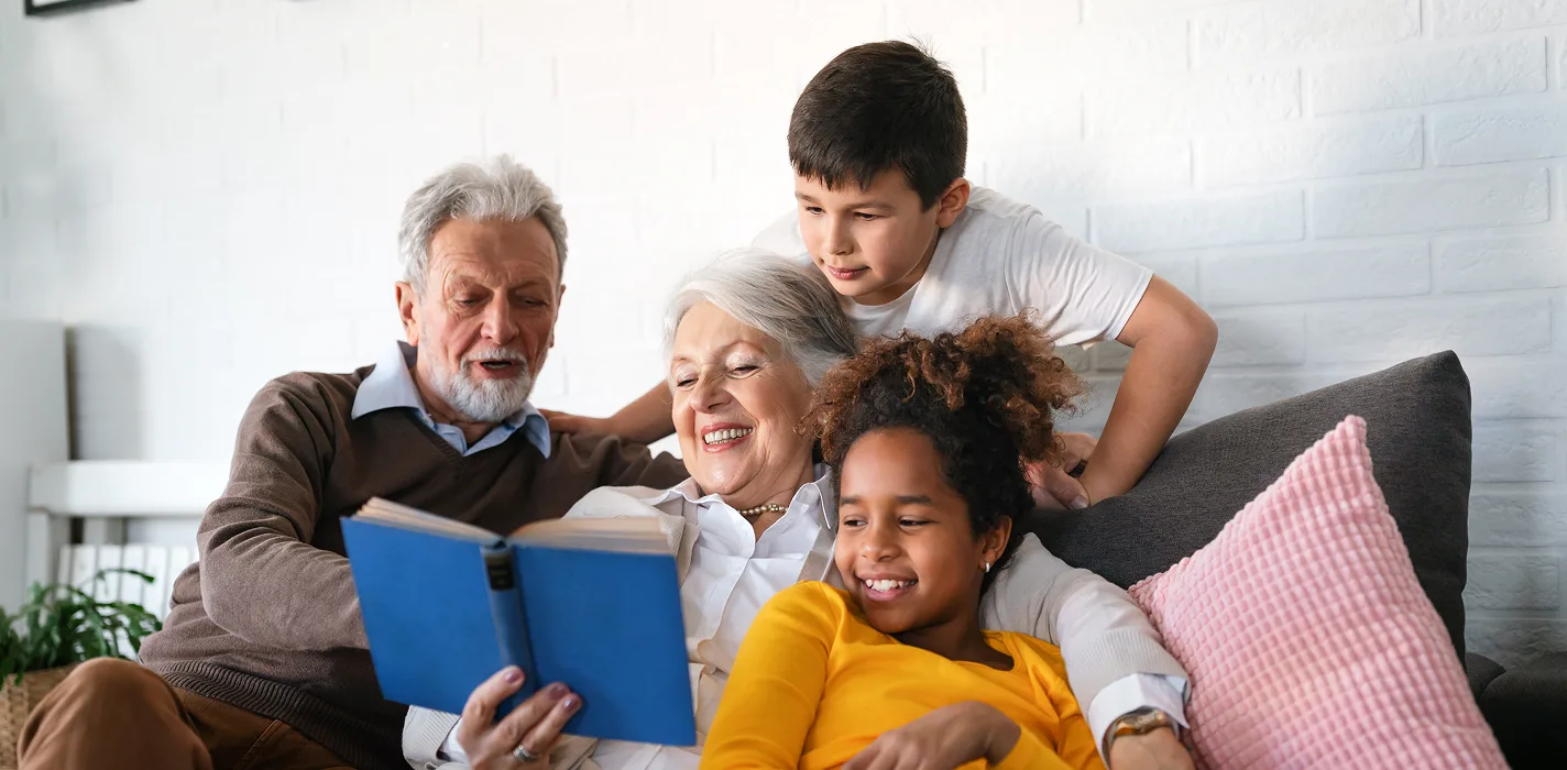 older couple reading to school-age children on a couch