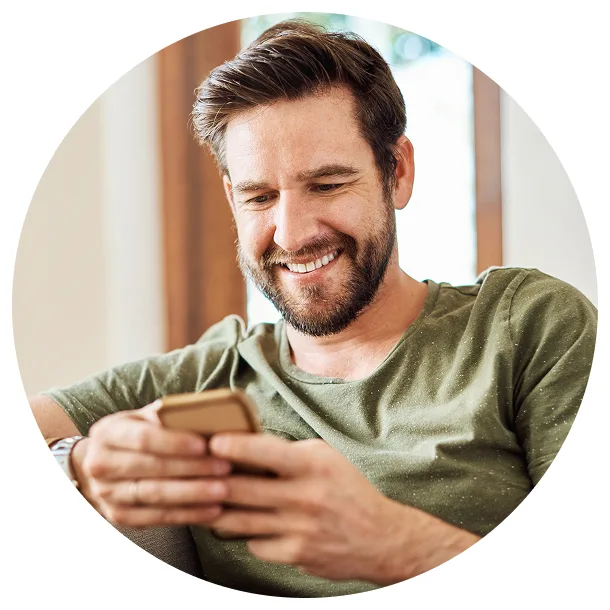 picture of a man smiling & looking at his phone