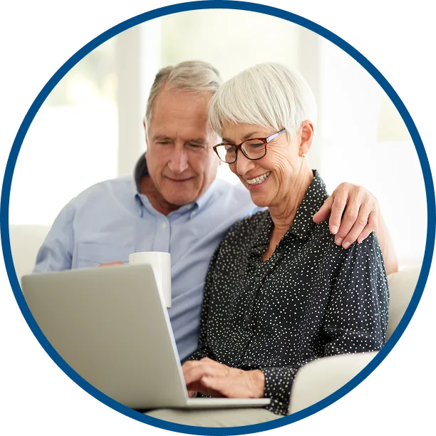 image of an older coupld smiling as they have coffee & look at someething on a laptop