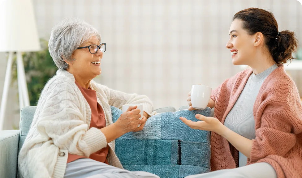 two women talking on a couch over coffee