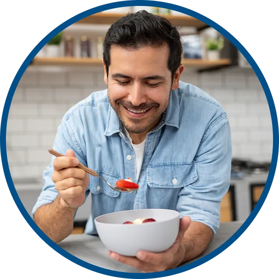 picture of a man smiling while he eats strawberries & yogurt