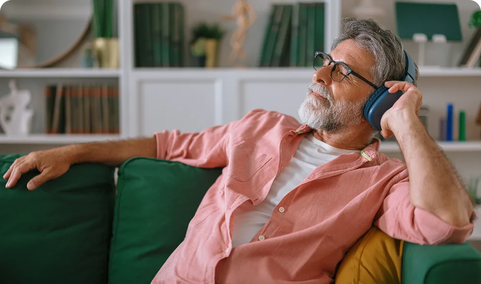 bearded guy listening to something on headphones with his eyes closed on the couch
