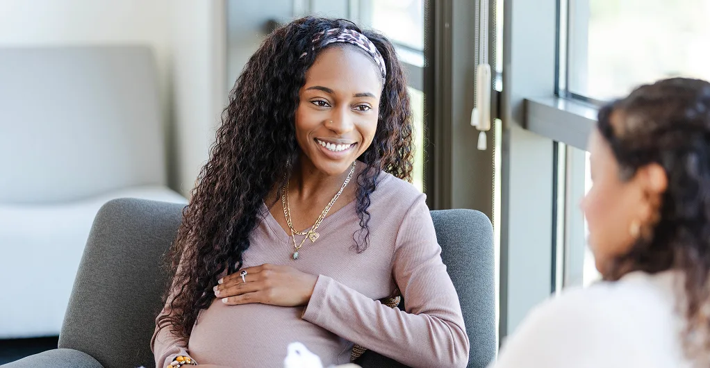 pregnant woman smiling & talking with another woman