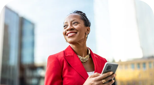 image of an older lady smiling at someone not in view wearing a sharp jacket & holding her smartphone