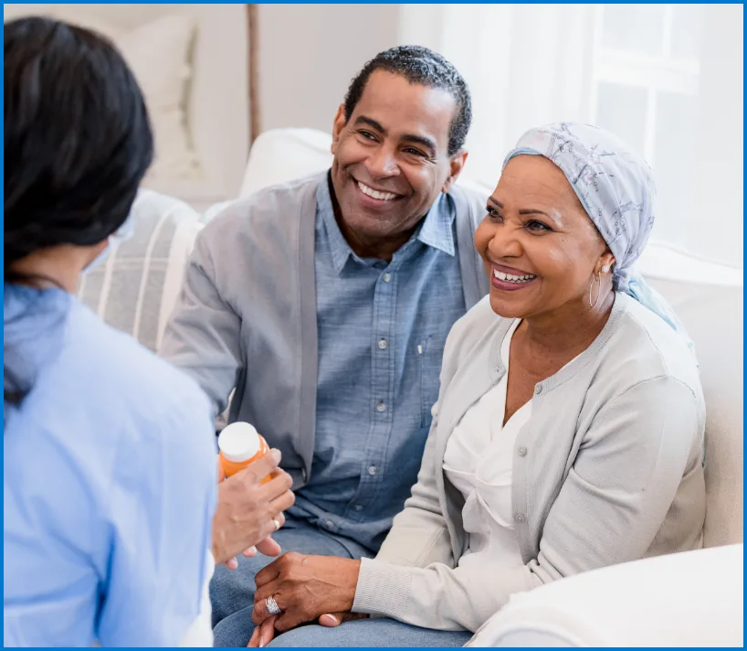 Couple sitting on couch smiling while speaking to nurse