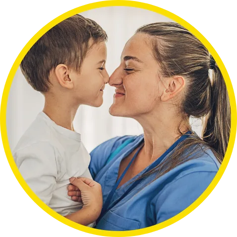 Female nurse smiling while rubbing noses with smiling child